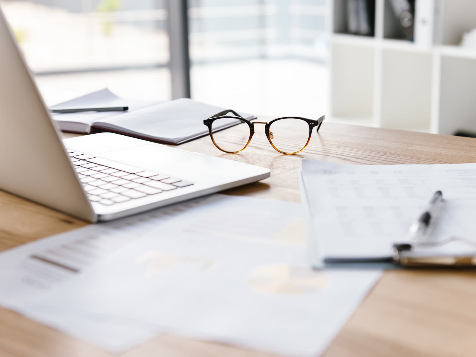 Escritorio de oficina con gafas, portátil y papeles