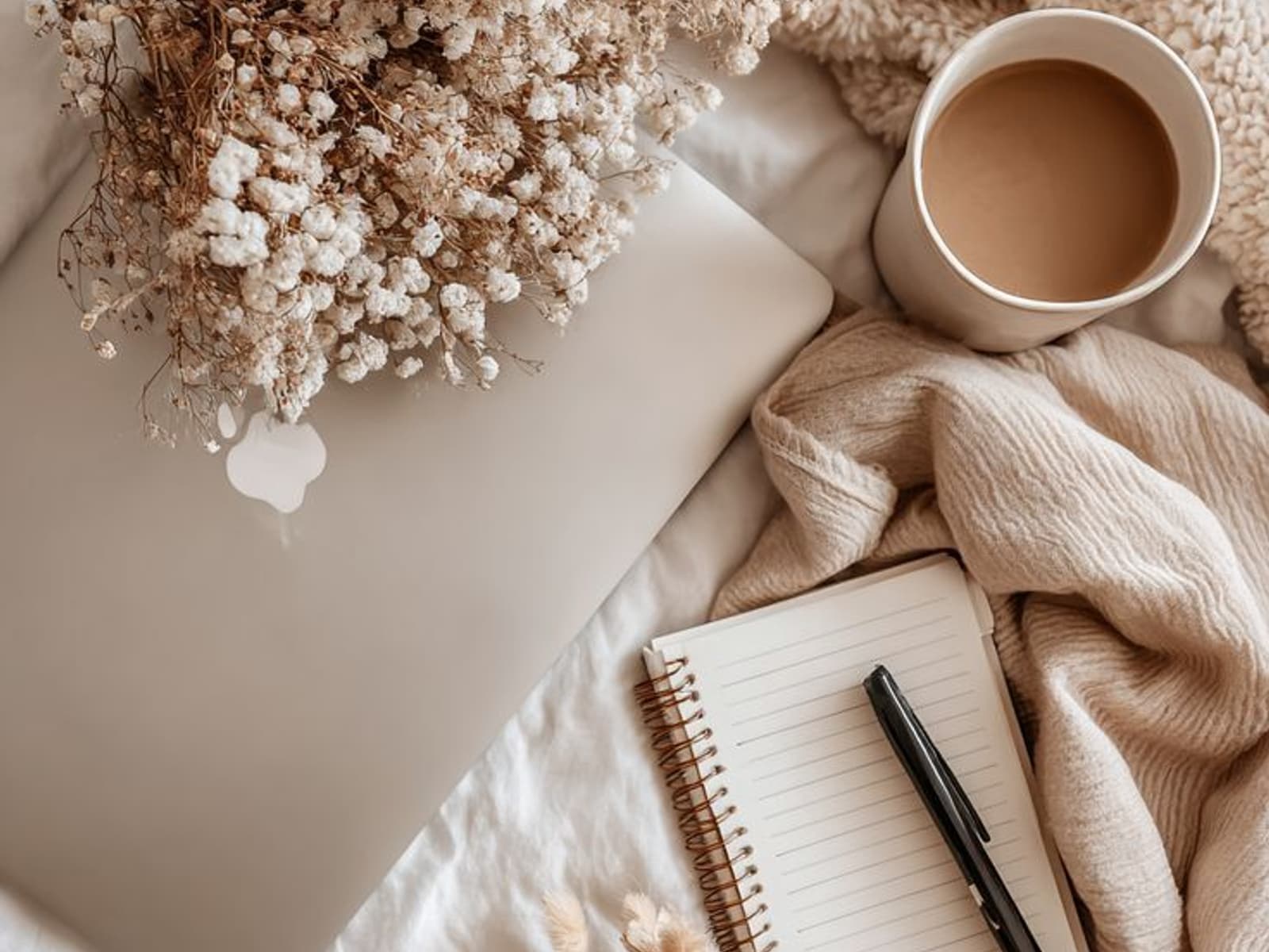 Escritorio con portátil, flores secas, café y una libreta